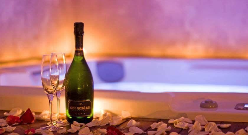 Een fles Cava Kripta Brut Reserva in een romantische sfeer bij een bubbelbad met rozenblaadjes